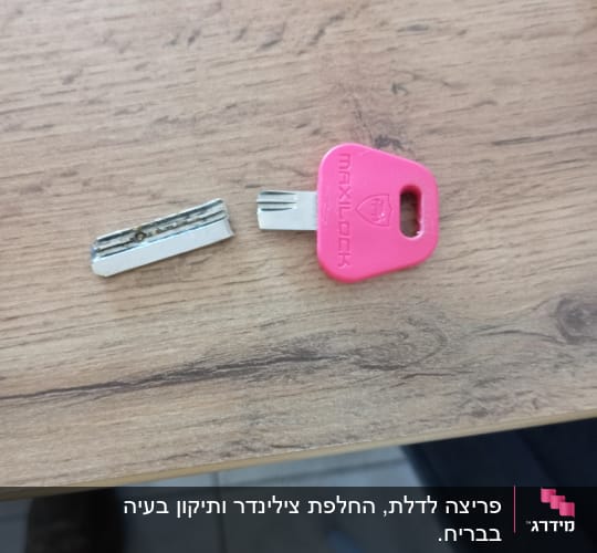 מפתח שבור עם ידית ורודה על שולחן עץ